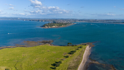 Aerial view of a coastal town with numerous sailboats anchored in a calm blue bay, under a clear...