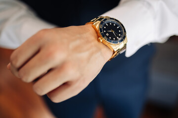 A man puts a classic mechanical watch on his hand, close-up. A man's hand and a wristwatch...