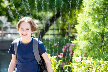 portrait of a happy boy against the background of a park and splashes of water