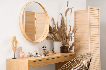 Decorative cosmetics with mirror on dressing table in room