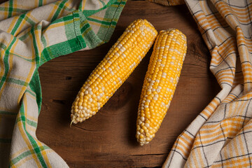 Two cobs sweet corn on wooden background..