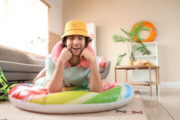 Male tourist with swim mattress lying at home on vacation