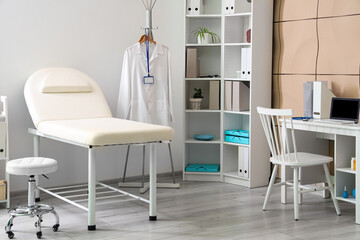 Interior of medical office with couch, shelf unit and doctor's workplace