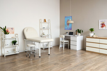 Interior of medical office with couch, shelf units and doctor's workplace