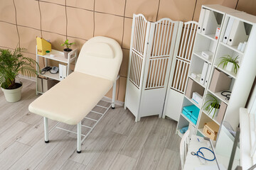 Interior of medical office with couch, folding screen and shelf units
