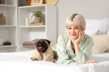 Young woman with pug dog lying in bedroom