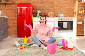 Beautiful young happy pin-up housewife cleaning supplies sitting in kitchen