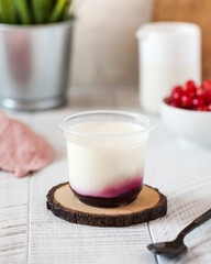 panna cotta or Greek yogurt with berry jam in a transparent plastic cup 