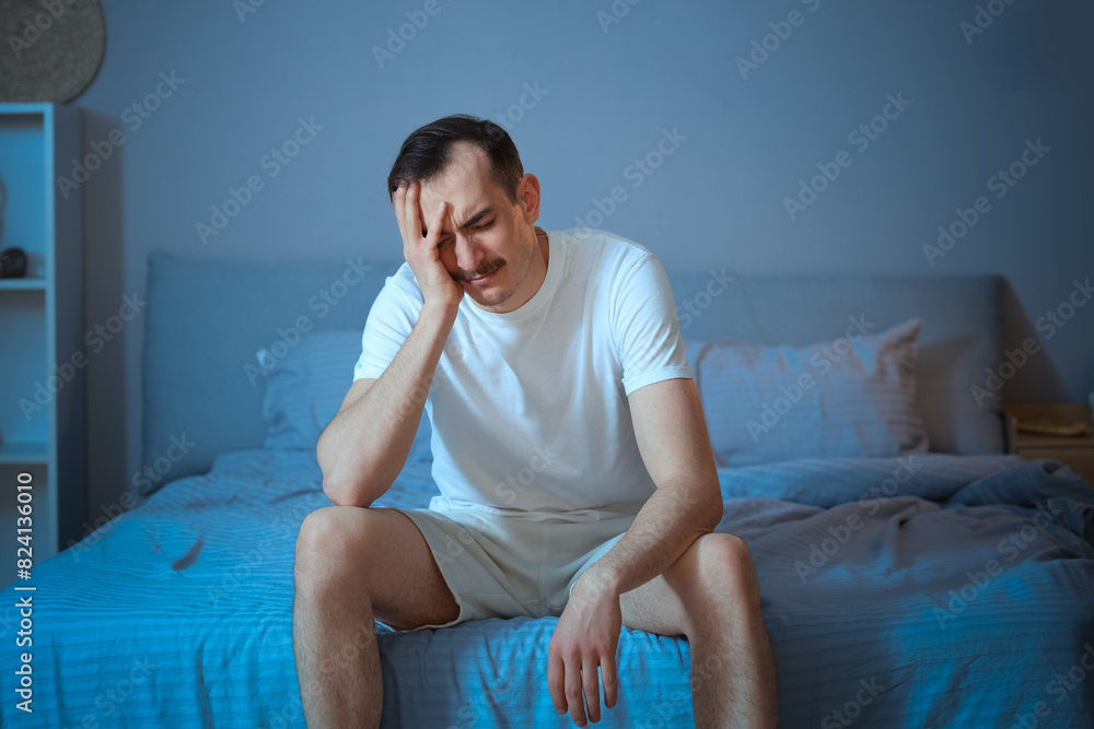 Wall mural Young man suffering from insomnia in bedroom at night