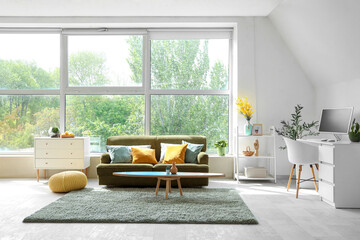 Interior of light living room with sofa, surfboard and workplace