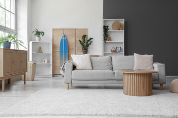 Interior of living room with sofa, shelf units and surfboard