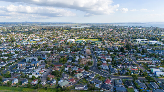 Aerial view of a suburban neighborhood with a construction site in the center, surrounded by residential houses and streets - South Auckland, New Zealand