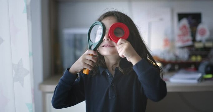 A young boy holding a pair of magnifying glasses up to his eyes, curiously observing his surroundings.