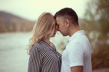 Couple standing forehead to forehead by the river.