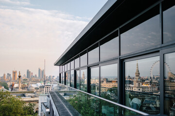 Modern London skyline reflected on glass facade, urban architecture with panoramic views