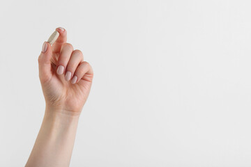 Woman holding vitamin pill on white background, closeup with space for text. Health supplement