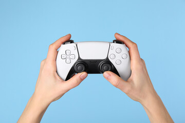 Woman using game controller on light blue background, closeup