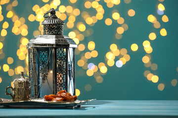Traditional Arabic lantern, dates and vintage cup holder on table against dark turquoise background...