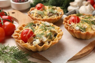 Tasty tartlets with cheese, tomatoes, mushrooms and dill on table, closeup