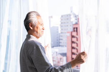 カーテンを開けるシニア男性　パジャマ