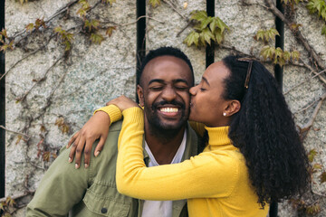 cute afro american couple kissing on the cheek and smiling