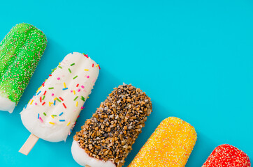 Summer composition of colorful ice cream popsicles on bright blue background with copy space. Minimal summer creative concept. Trendy sweet food summertime layout. Ice cream aesthetic. Flat lay.