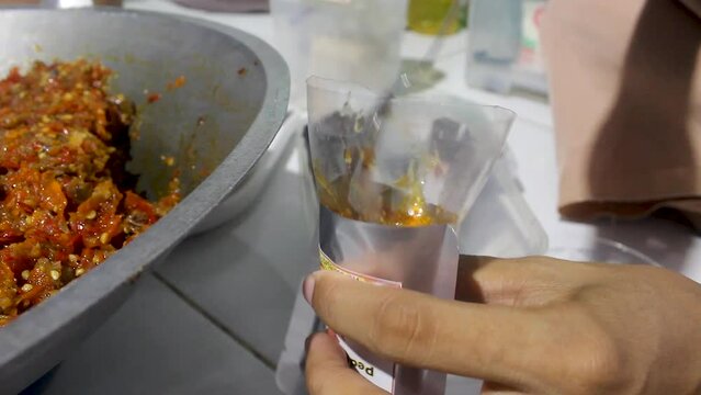 The process of packing squid sauce manually.