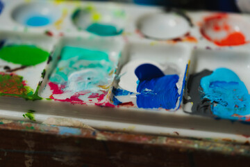 mix of colors paints and brushes in a pallet from an artist