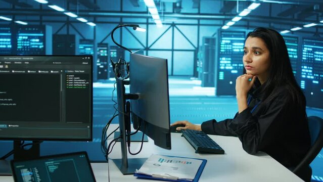 IT engineer in data center using PC to find misconfigurations affecting rackmounts performance. Woman checking servers bottlenecks leading to sluggish data transfer rates and malfunctions