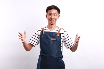 Smiling asian waiter in blue apron holding your logo or box, spread hands as if carry something...