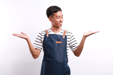 Asian young man wearing apron over white background smiling showing both hands open palms,...