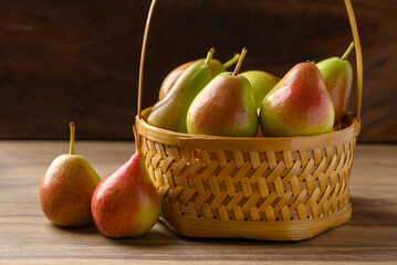 Fresh pear fruit in natural basket on wooden background