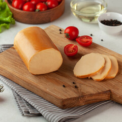 Smoked cheese log presented on a rustic wooden slice, styled with fresh tomatoes