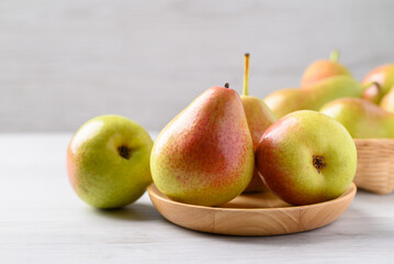 Fresh pear fruit on wooden plate with white table