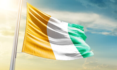 Ivory Coast national flag waving in beautiful sky.