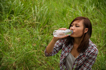 Young Woman Drinking Water bottle outdoor park traveler. Asian female drinking water bottle healthy...