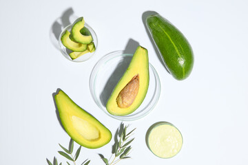 A half of avocado placed on glass petri dish arranged with two petri dishes of avocado cream and avocado slices. Avocados contain a B complex vitamin commonly called biotin