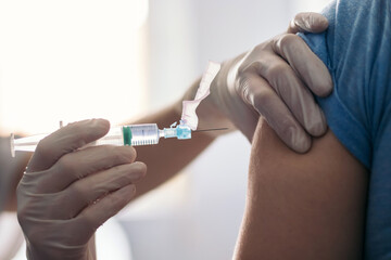 Vaccine in injection needle. Doctor working with patient's arm. Physician or nurse giving...