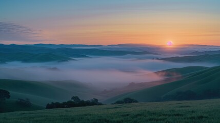 A panoramic view of rolling hills covered in mist during a calm morning sunrise. 