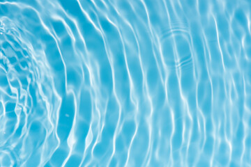 Blue water with ripples on the surface. Defocus blurred transparent blue colored clear calm water surface texture with splashes and bubbles. Water waves with shining pattern texture background.