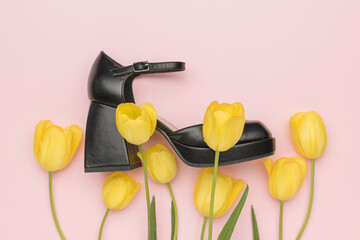 Black High Heel Surrounded by Yellow Tulips on Pastel Pink Background