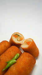 Risoles, traditional snack form Indonesia. It filled with carrot, potato, chicken and other vegetables rolled in breadcrumbs then deep fried, served with green chili on a plate on white background.
