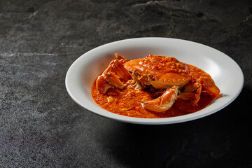 traditional chinese wok fried seafood fresh big meat crab with chilli spicy salted egg yolk cheese cream sauce in plate on dark stone table asian cafe hotel luxury halal food restaurant banquet menu