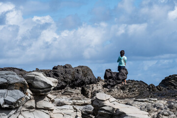 Woman tourist enjoying the view at Dragon’s Teeth, fascinating trachyte lava rock geology where it flows into the Pacific Ocean, Makalua-Puna Point, Maui, Hawaii
