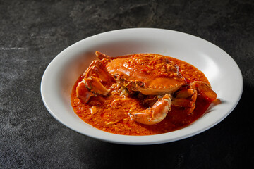 traditional chinese wok fried seafood fresh big meat crab with chilli spicy salted egg yolk cheese cream sauce in plate on dark stone table asian cafe hotel luxury halal food restaurant banquet menu