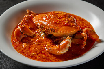 traditional chinese wok fried seafood fresh big meat crab with chilli spicy salted egg yolk cheese cream sauce in plate on dark stone table asian cafe hotel luxury halal food restaurant banquet menu