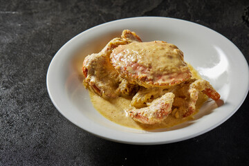 traditional chinese wok fried seafood fresh big meat crab with chilli spicy salted egg yolk cheese cream sauce in plate on dark stone table asian cafe hotel luxury halal food restaurant banquet menu