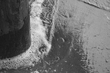 Fototapeta premium seafoam on a wood post and wet sand