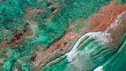 Aerial View of Waves Breaking over Orange Coral Reef Rocks