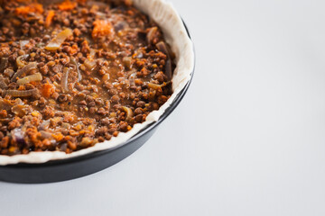 plant-based lentil and pumpkin pie with filling just poured into the pastry before cooking it